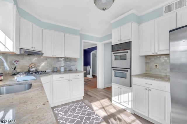 kitchen featuring light stone countertops, appliances with stainless steel finishes, white cabinets, and backsplash