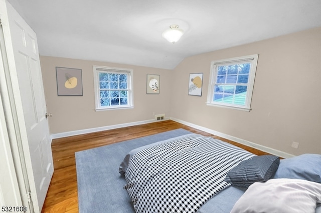 bedroom with light hardwood / wood-style flooring, vaulted ceiling, and multiple windows