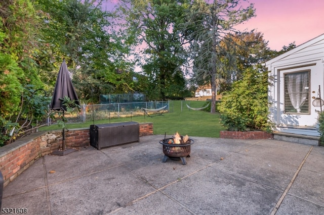 patio terrace at dusk with a fire pit and a lawn