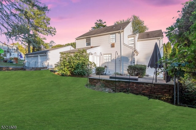 back house at dusk with a lawn