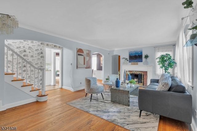 living room with crown molding, hardwood / wood-style floors, and a brick fireplace