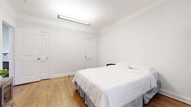 bedroom with hardwood / wood-style flooring and crown molding