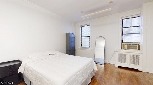 bedroom with hardwood / wood-style flooring, cooling unit, and radiator heating unit