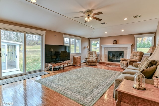 living room with a fireplace, a wealth of natural light, lofted ceiling, and light hardwood / wood-style floors