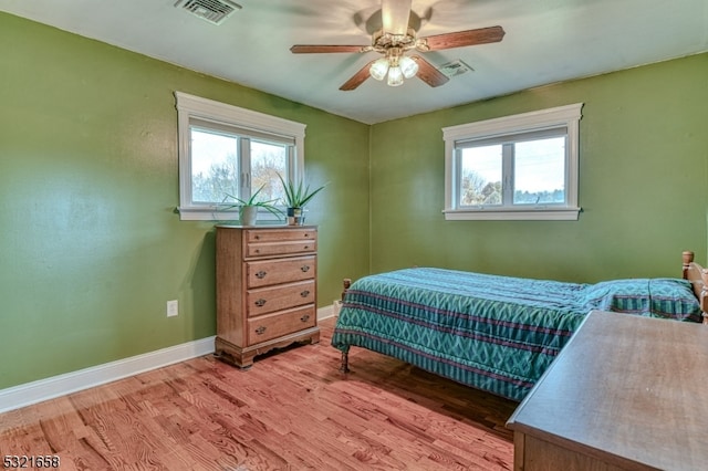 bedroom with multiple windows, hardwood / wood-style floors, and ceiling fan