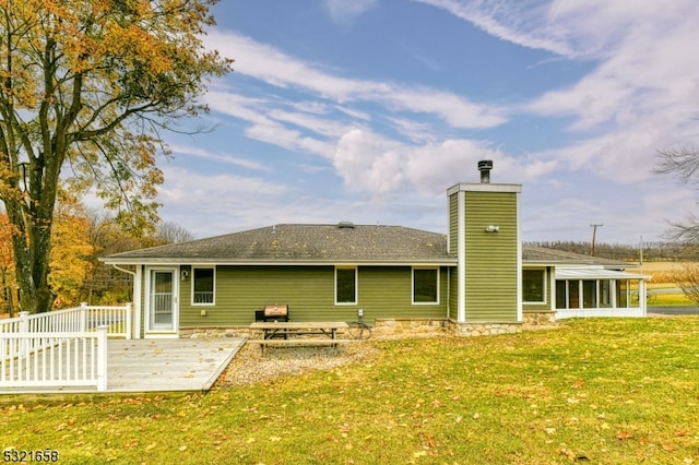 rear view of house featuring a sunroom, a lawn, and a wooden deck