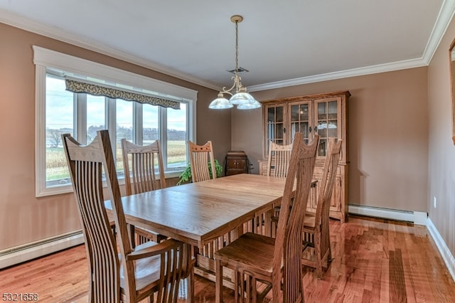 dining room featuring hardwood / wood-style floors, baseboard heating, crown molding, and a notable chandelier