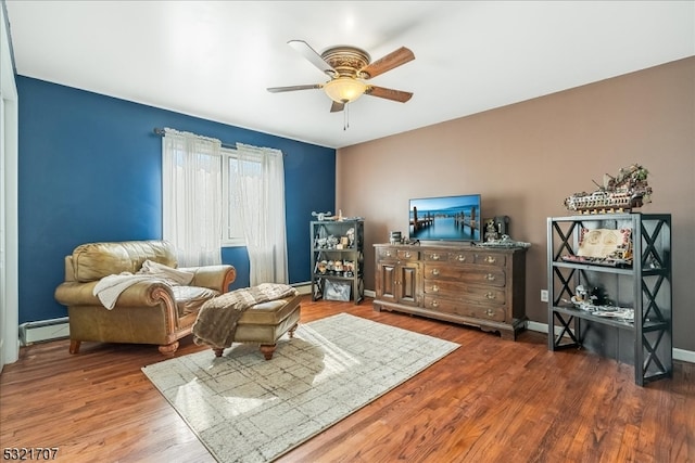 living area with ceiling fan, dark hardwood / wood-style flooring, and a baseboard heating unit