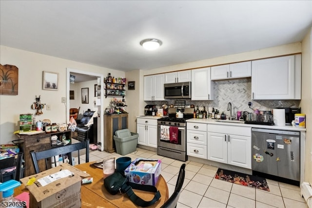 kitchen featuring sink, white cabinetry, light tile patterned floors, appliances with stainless steel finishes, and tasteful backsplash