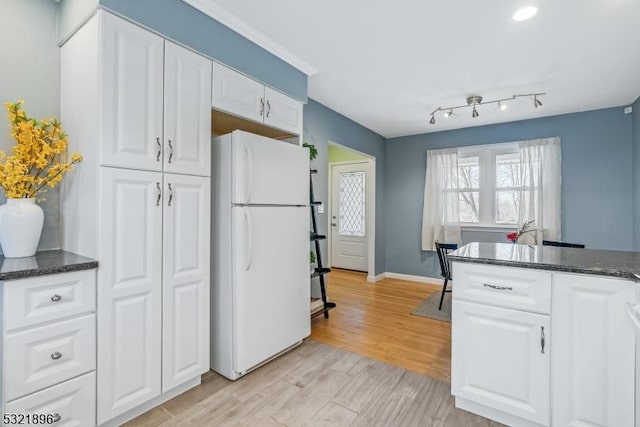 kitchen with light wood finished floors, baseboards, white cabinets, and freestanding refrigerator