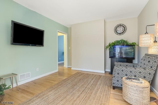 living area with baseboards, visible vents, and wood finished floors