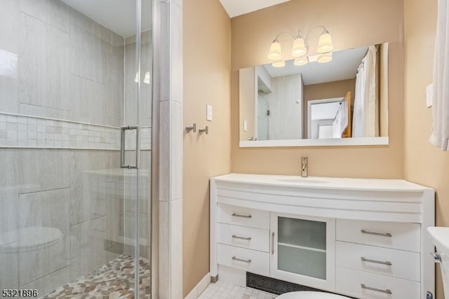 bathroom with toilet, a shower stall, baseboards, and vanity