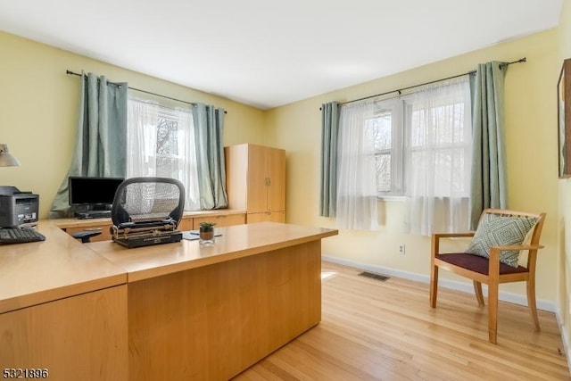 home office featuring light wood-style flooring, visible vents, and baseboards