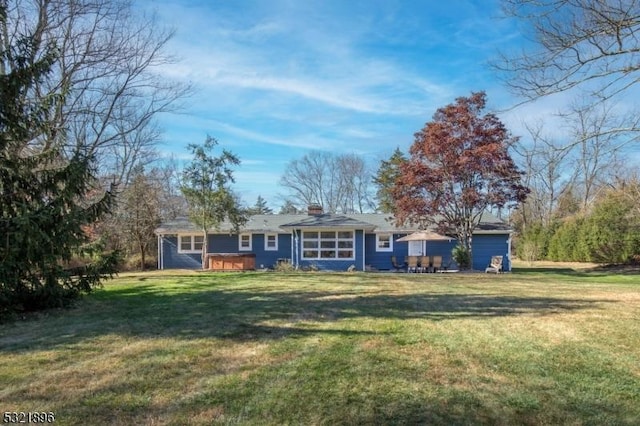 view of front of home featuring a chimney, a front yard, and a jacuzzi