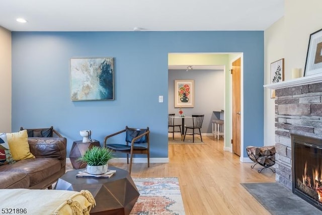 living room featuring light wood-style floors, a fireplace, and baseboards