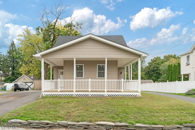 bungalow-style home featuring a porch, an outdoor structure, a garage, and a front lawn