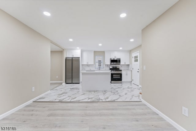 kitchen with white cabinetry, light hardwood / wood-style floors, appliances with stainless steel finishes, and decorative backsplash