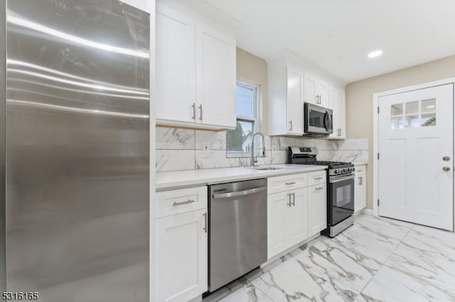 kitchen with stainless steel appliances, decorative backsplash, sink, and white cabinets