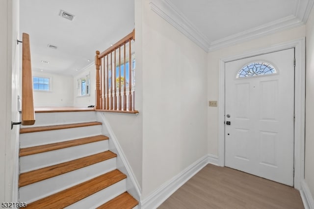 entrance foyer with light hardwood / wood-style flooring, crown molding, and a wealth of natural light