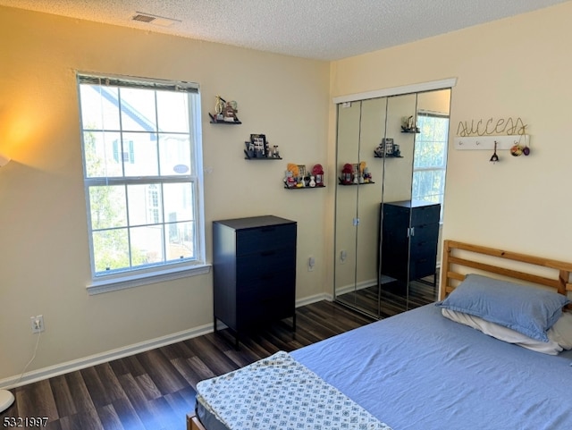 bedroom featuring dark wood-type flooring, a textured ceiling, and a closet