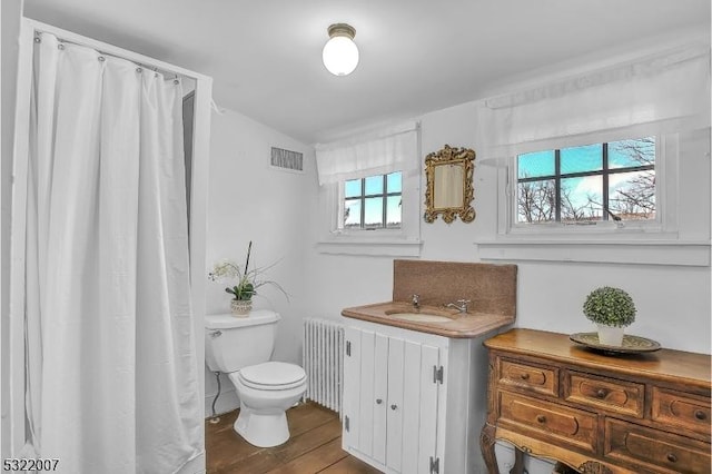 bathroom featuring hardwood / wood-style floors, radiator, sink, and toilet