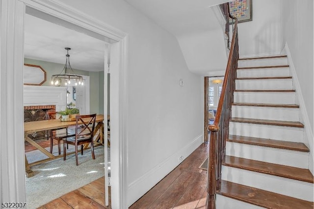 stairway featuring hardwood / wood-style flooring and a brick fireplace