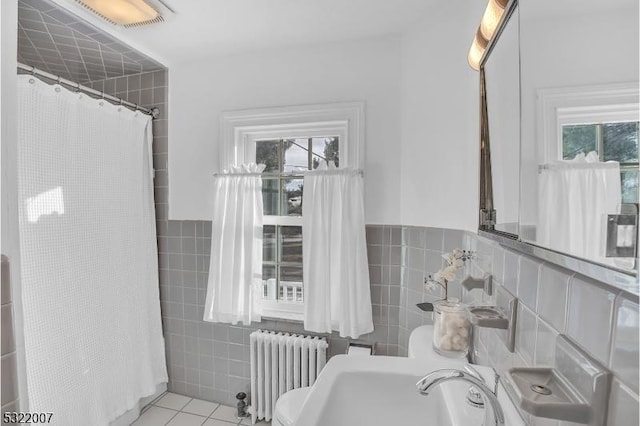 bathroom featuring walk in shower, tile patterned floors, sink, tile walls, and radiator