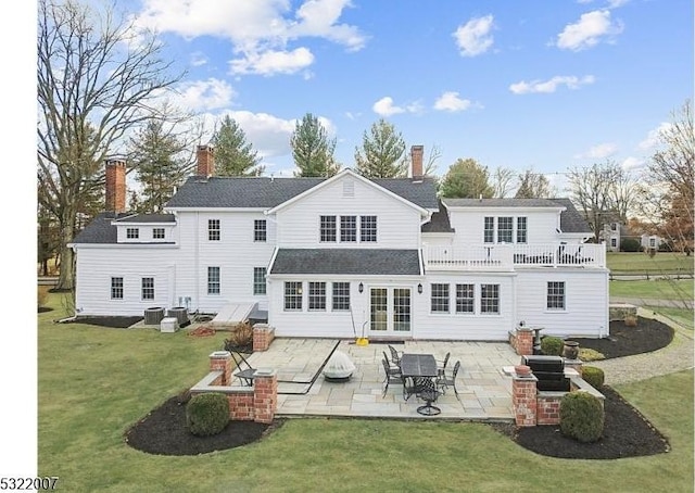 rear view of property featuring french doors, a balcony, central AC unit, a yard, and a patio