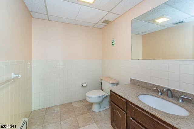 74 S Powder Mill Rd, Parsippany-Troy Hills Twp, NJ 07950 - bathroom with tile walls, toilet, a drop ceiling, vanity, and a baseboard heating unit