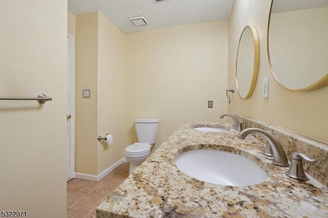 bathroom with a sink, toilet, wood finished floors, and a textured ceiling