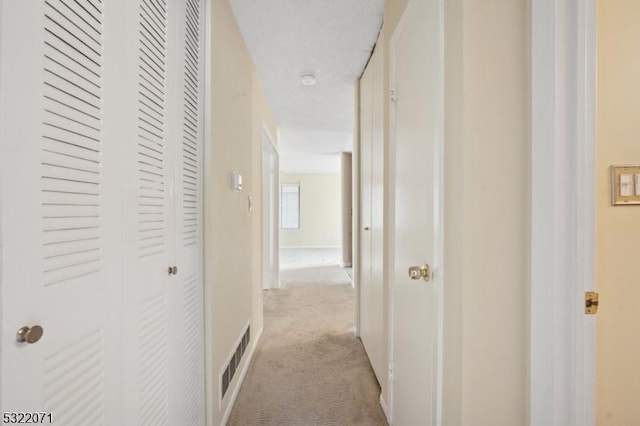 hall featuring baseboards and light carpet