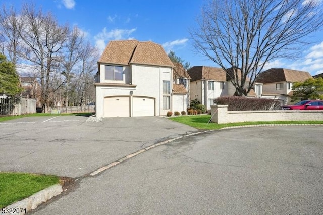 view of front of property featuring stucco siding, a residential view, an attached garage, and aphalt driveway