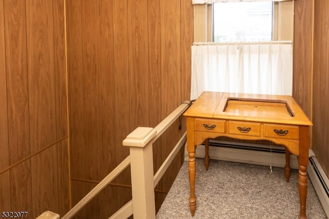 interior space featuring wood walls, a baseboard heating unit, and carpet