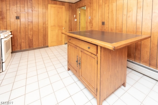 kitchen with wood walls, white range oven, a kitchen island, and light tile patterned floors