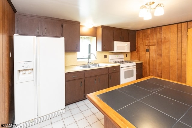 kitchen with tile countertops, wood walls, sink, light tile patterned floors, and white appliances