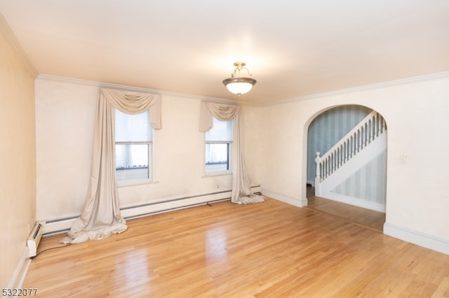 spare room featuring wood-type flooring, baseboard heating, and crown molding