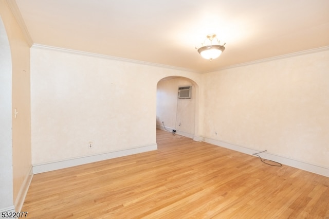 spare room with a wall unit AC, hardwood / wood-style flooring, and crown molding