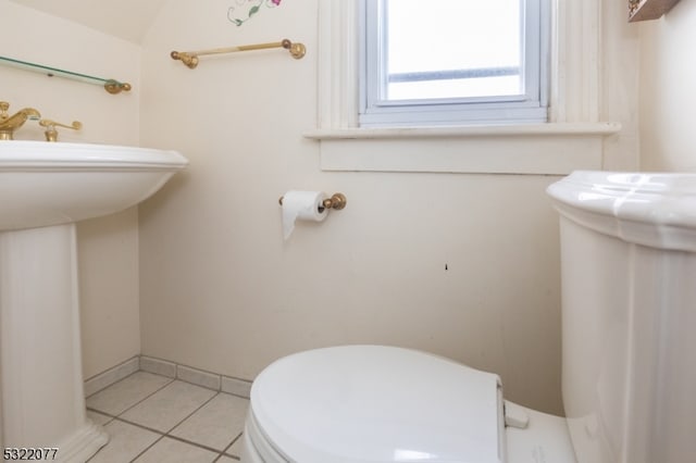 bathroom with toilet, sink, and tile patterned flooring