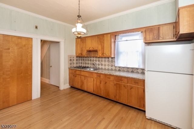 kitchen with ornamental molding, hanging light fixtures, light hardwood / wood-style flooring, white refrigerator, and decorative backsplash