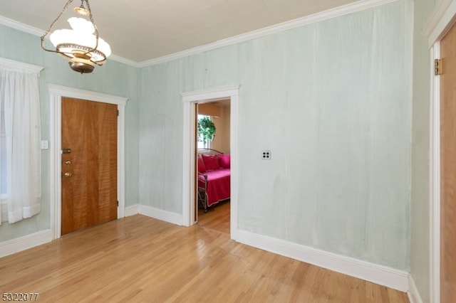 unfurnished room featuring hardwood / wood-style flooring, an inviting chandelier, and ornamental molding