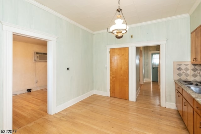 kitchen featuring a notable chandelier, tasteful backsplash, ornamental molding, light wood-type flooring, and decorative light fixtures