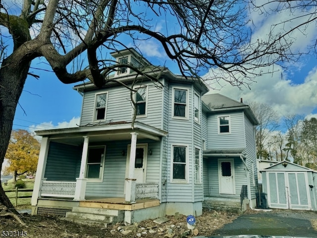 back of house featuring covered porch and a storage unit