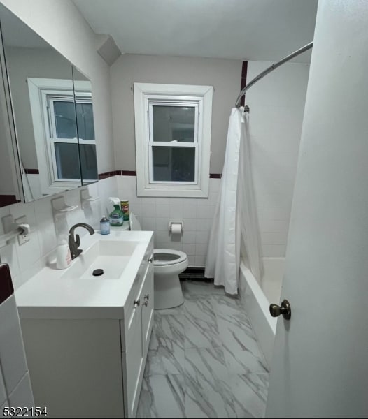 full bathroom with toilet, vanity, tile walls, and shower / tub combo