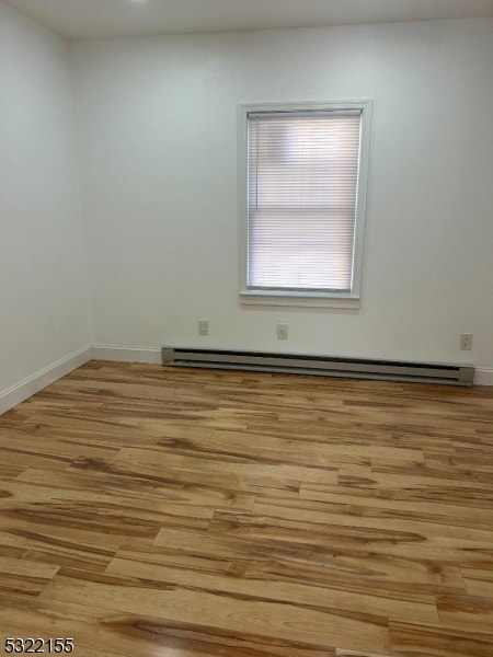 unfurnished room with light wood-type flooring, a baseboard radiator, and baseboards