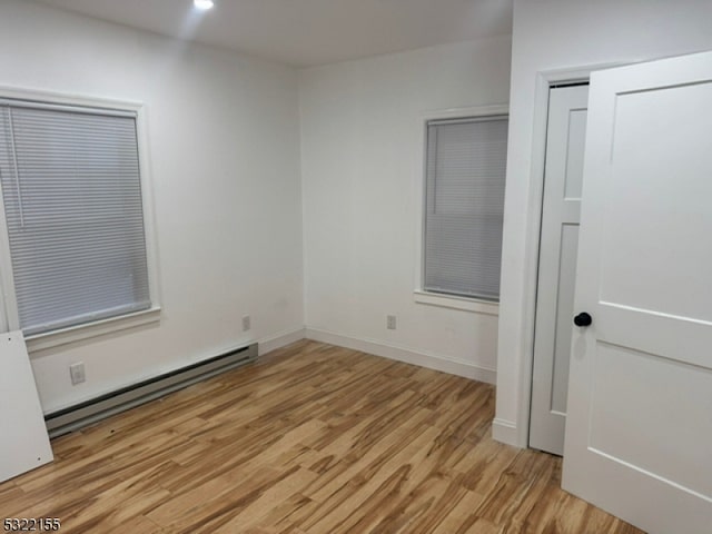 unfurnished bedroom with baseboards, light wood-style floors, a baseboard heating unit, a closet, and recessed lighting