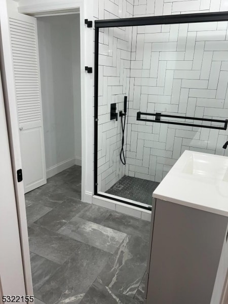 full bath featuring marble finish floor, a stall shower, vanity, and baseboards