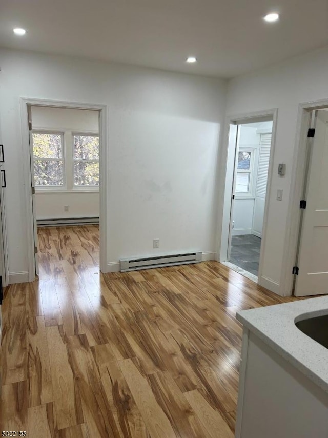 empty room featuring light wood-type flooring, a baseboard heating unit, baseboard heating, and recessed lighting