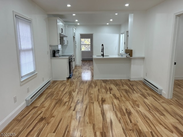 kitchen with a baseboard radiator, light wood finished floors, electric range, and light countertops