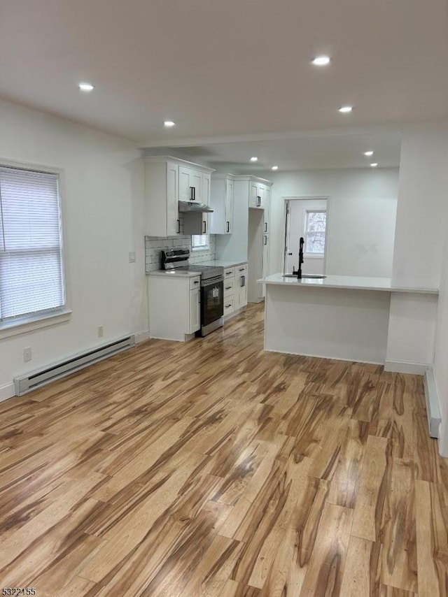 kitchen with electric stove, a baseboard radiator, light countertops, light wood-style floors, and a sink