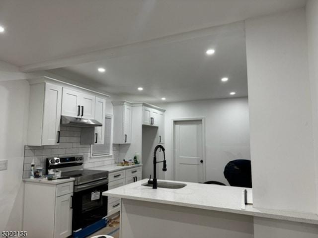 kitchen featuring electric range, a sink, under cabinet range hood, backsplash, and recessed lighting